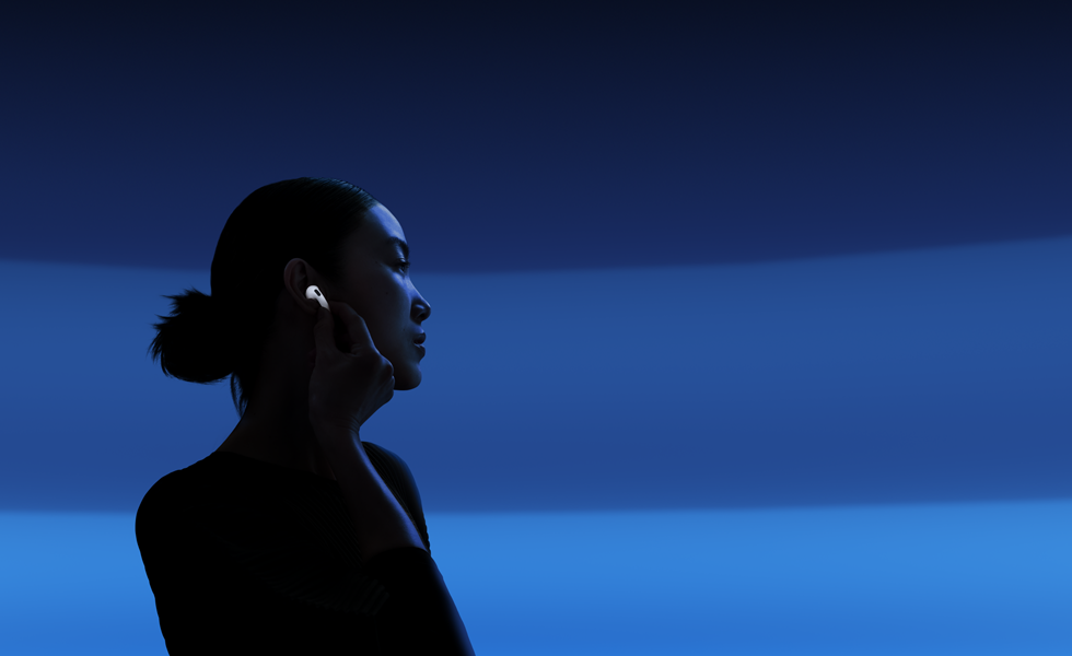 Une personne tenant la tige de ses AirPods 5 entre le pouce et l'index pour changer les modes d'écoute