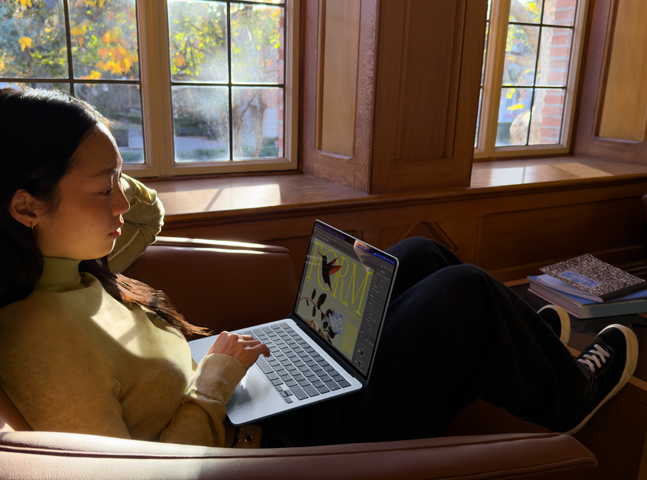 Une personne assise sur une chaise utilise son MacBook Air