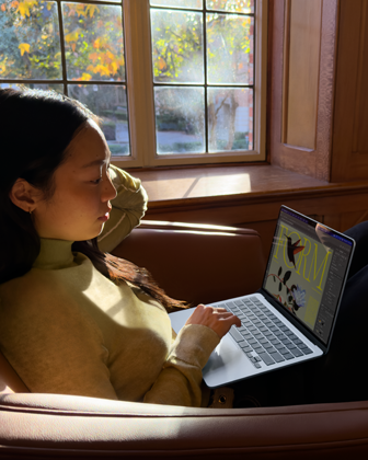 Une personne assise sur une chaise utilise son MacBook Air