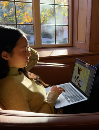 Une personne assise sur une chaise utilise son MacBook Air