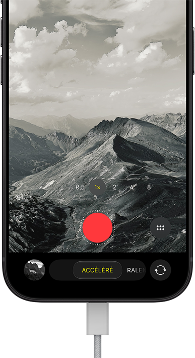 iPhone 18 Pro, face avant, affichant un paysage montagneux, avec le mode caméra incrusté en mode Accéléré, avec câble d'alimentation branché sur le port de charge