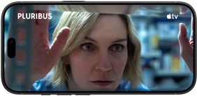 iPhone 18 Pro, mode paysage, affichant un gros plan d'une femme regardant à travers une étagère. Nom de la série : Pluribus