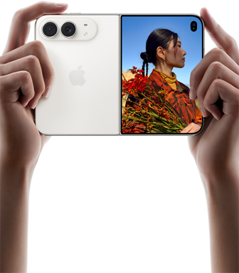 iPhone Duo, finition blanc stellaire, tenu à deux mains en position horizontale, déplié, le volet extérieur gauche présente les caméras arrière Fusion 48 MP, le volet extérieur droit présente l'écran externe affichant une personne qui se fait photographier et peut voir son propre visage pendant la prise de vue à l'aide de Duo Preview
