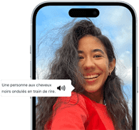 Un iPhone 15 affichant une annonce VoiceOver décrivant le contenu d'une photographie en ces termes : une personne aux cheveux noirs ondulés en train de rire