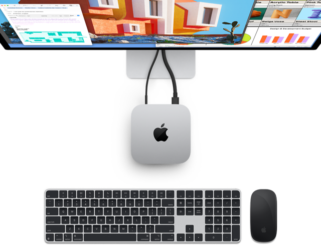 Dessus du Mac mini en finition argent avec le logo Apple, connecté à un moniteur et situé à côté d'un Magic Keyboard sans fil et d'une Magic Mouse