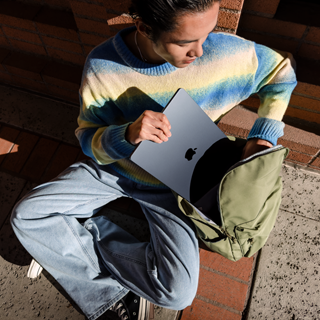 Vue de face d'une personne glissant un MacBook Air 15 pouces fermé dans un sac