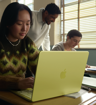 Une étudiante utilise un MacBook Neo, couleur jaune agrume, débranché, dans une salle de classe