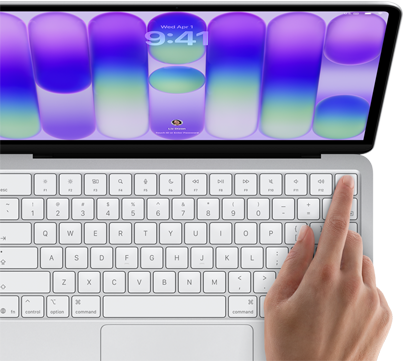 MacBook Neo, couleur argent, affichant l'écran de connexion, doigt d'une personne sur le capteur Touch ID situé dans le coin supérieur droit du clavier