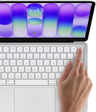 MacBook Neo, couleur argent, affichant l'écran de connexion, doigt d'une personne sur le capteur Touch ID situé dans le coin supérieur droit du clavier