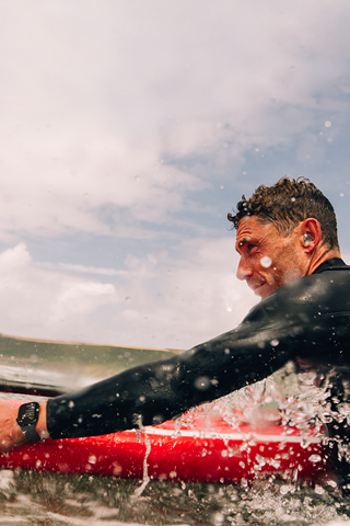 Un homme sur une planche de paddle, dans l'eau, porte une Apple Watch Series 10.